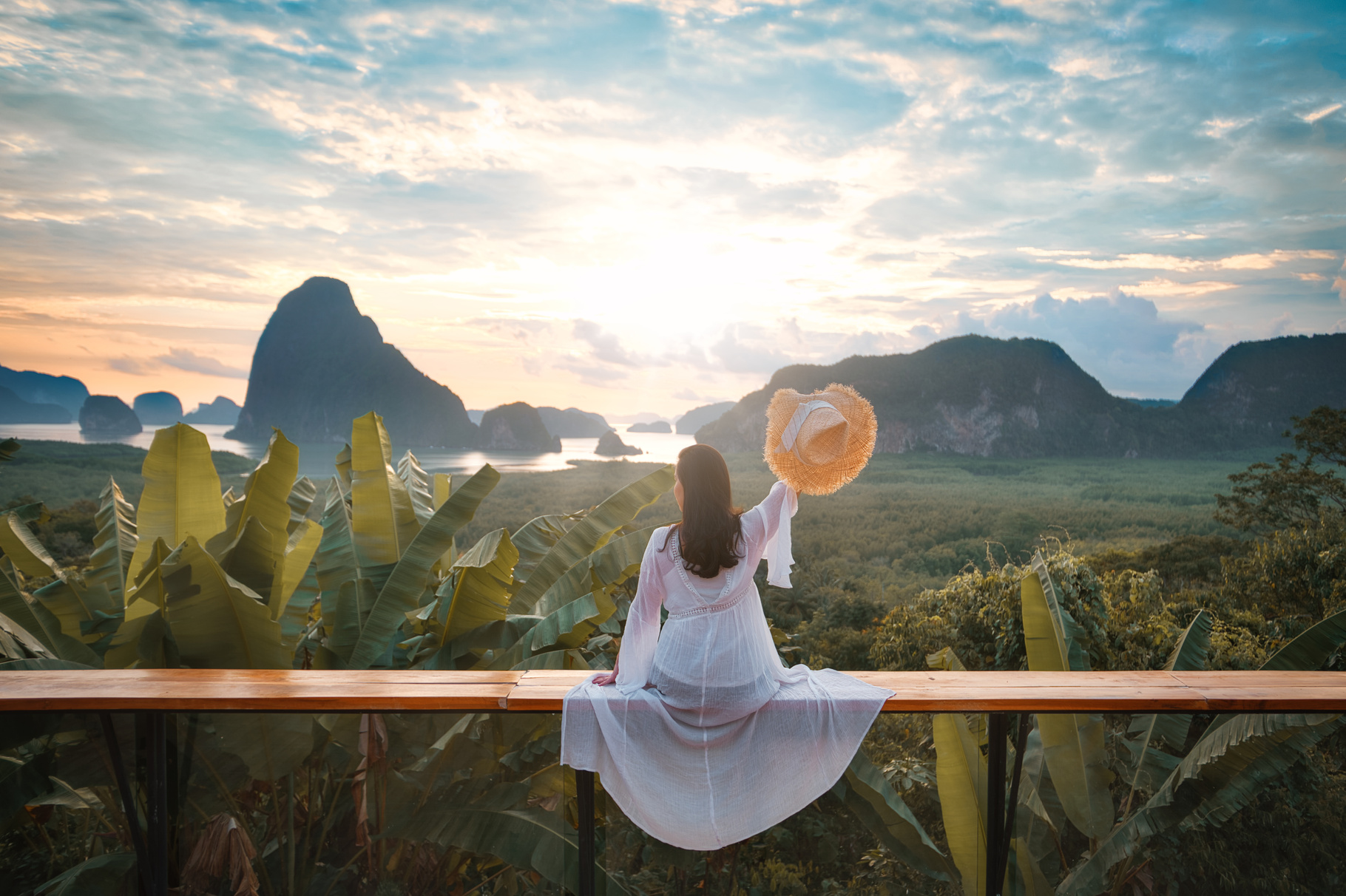 Woman in White Dress and Hat Sitting Outdoors with Nature